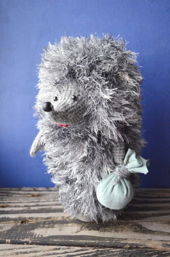 Soft toy hedgehog. Handmade knitted hedgehog isolated on blue background royalty free stock photo