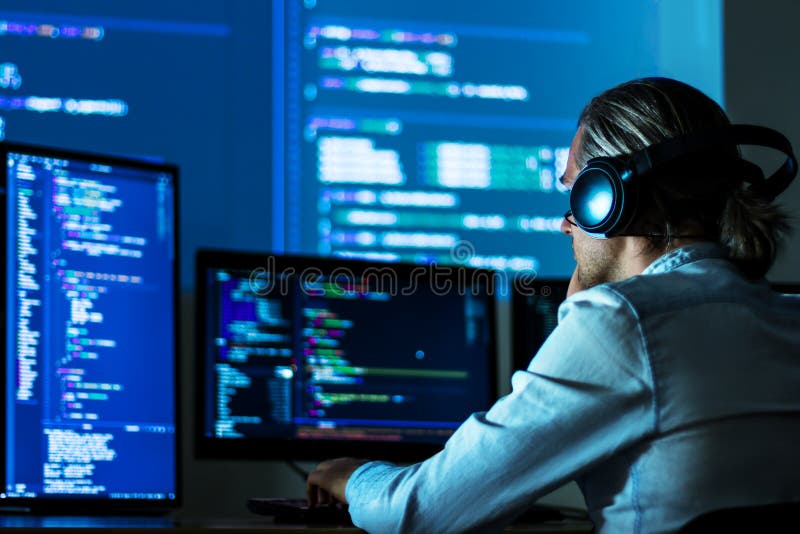 Software developer freelancer man male in headphones work with program code C++ Java Javascript on wide displays at night Develops new web desktop mobile application or framework. Projector background. Program coding working stock images, royalty-free photos and pictures