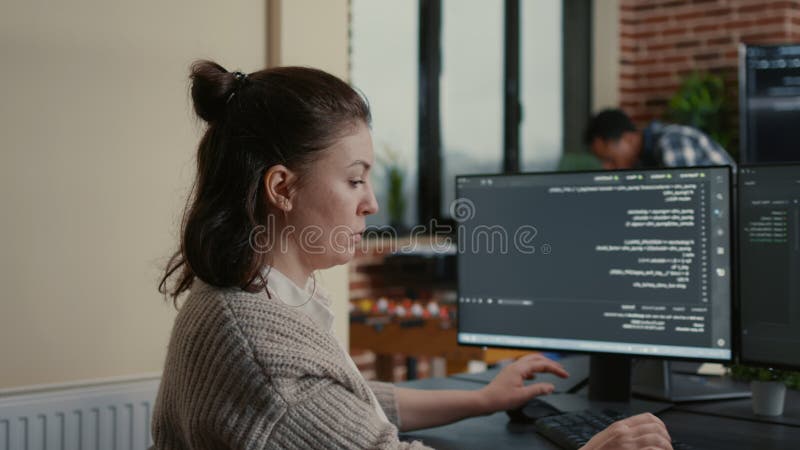Software developer writes programming code at an office workstation, reviewing algorithms, data systems and software development tasks, during a software support task. Code programming video