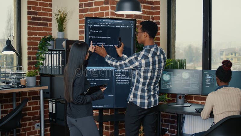 Software engineers analyzing code on wall screen tv comparing errors using digital tablet stock photos
