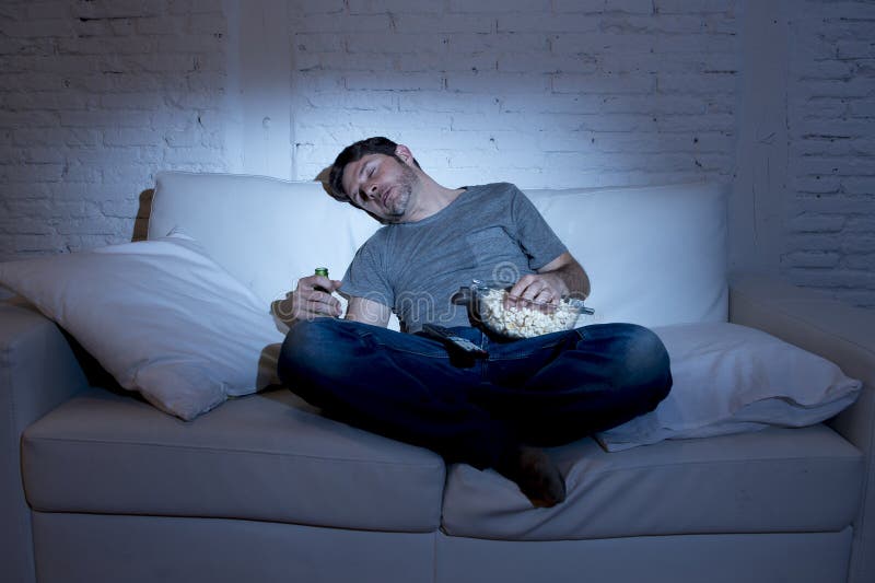 Sofá do homem novo em casa na sala de visitas que dorme ao olhar o filme ou o esporte na tevê na noite fotografia de stock royalty free Sofá do homem novo em casa na sala de visitas que dorme ao olhar o filme ou o esporte na tevê na noite fotografia de stock royalty free