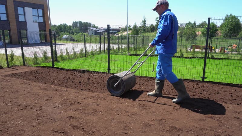 Soil compaction roller manually after seeding sow lawn in yard. Gimbal movement