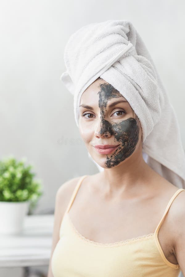 Soins de la peau de visage Jeune femme attirante enveloppée en serviette de Bath, appliquant le masque de boue d'argile pour fair photos libres de droits Soins de la peau de visage Jeune femme attirante enveloppée en serviette de Bath, appliquant le masque de boue d'argile pour fair photos libres de droits