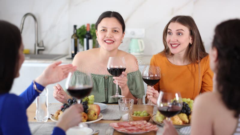 Soirée décontractée où un groupe de biscuits joyeux et insouciants partageant le vin dîner ensemble et bavarder dans une cuisine c banque de vidéos