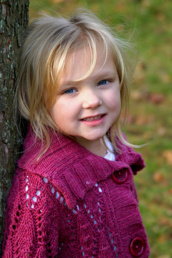 Beautiful little blonde girl leaning against tree. Beautiful little blonde girl leaning against tree