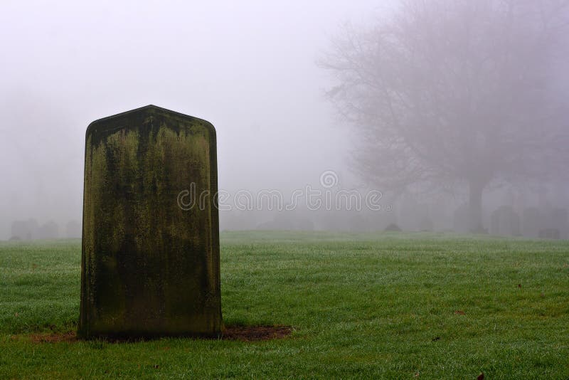 Single gravestone in a spooky graveyard on a foggy winter day. Single gravestone in a spooky graveyard on a foggy winter day