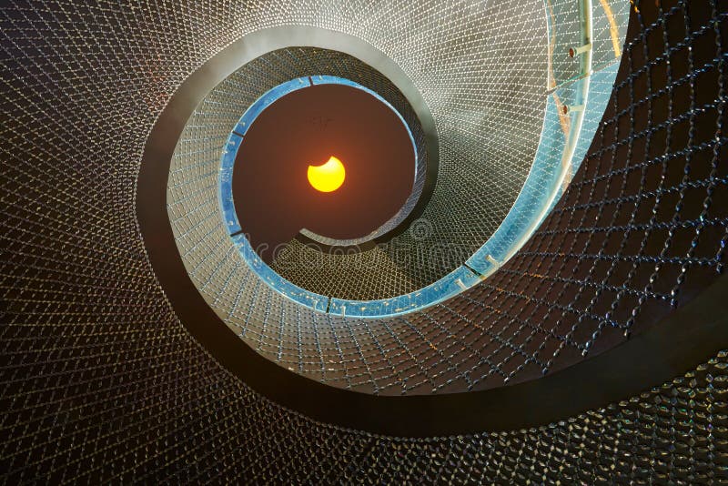 Solar eclipse seen from rotative stair. Low angle view of a luxury rotation stair directing to partial solar eclipse out above the sky Solar eclipse seen from rotative stair. Low angle view of a luxury rotation stair directing to partial solar eclipse out above the sky
