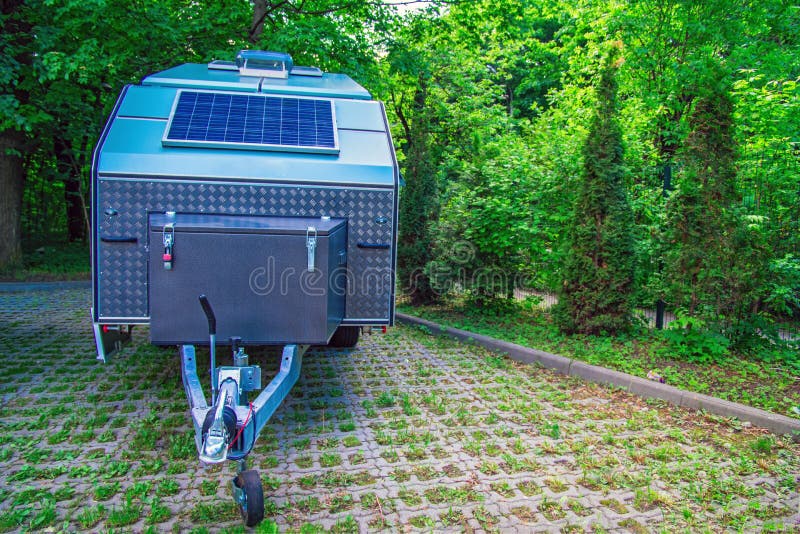 Solar panel is fixed on the tourist trailer. Off-road trailer stands in the parking lot on the background of thick green foliage. royalty free stock image Solar panel is fixed on the tourist trailer. Off-road trailer stands in the parking lot on the background of thick green foliage. royalty free stock image
