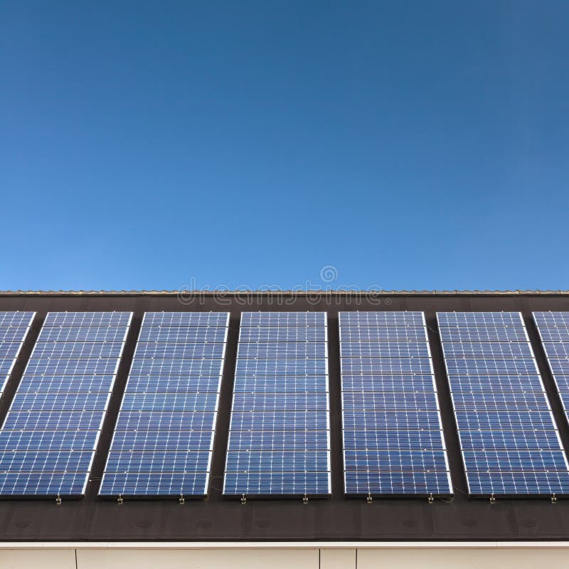 Solar panels in a row on a roof with a blue sky
