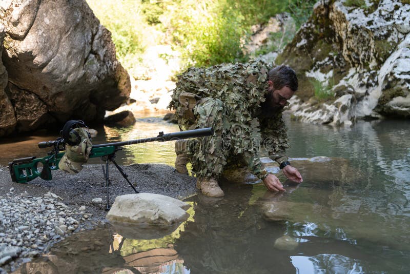 Soldado Con Uniforme De Traje De Camuflaje Tomando Agua Fresca Del Río. Rifle De Francotirador Militar a Un Lado. Foto - Imagen de fuerzas, ejército: 264702524