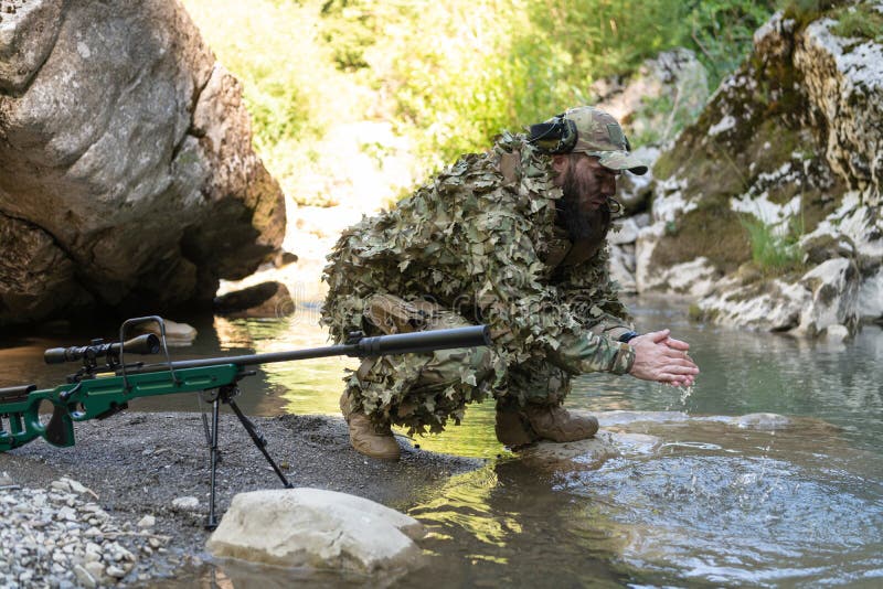 Soldado Con Uniforme De Traje De Camuflaje Tomando Agua Fresca Del Río. Rifle De Militar a Un Lado. de archivo - Imagen camuflaje, selva: 264702555