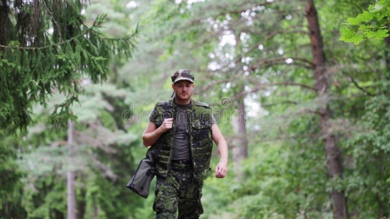 Soldado o cazador joven con el arma en bosque