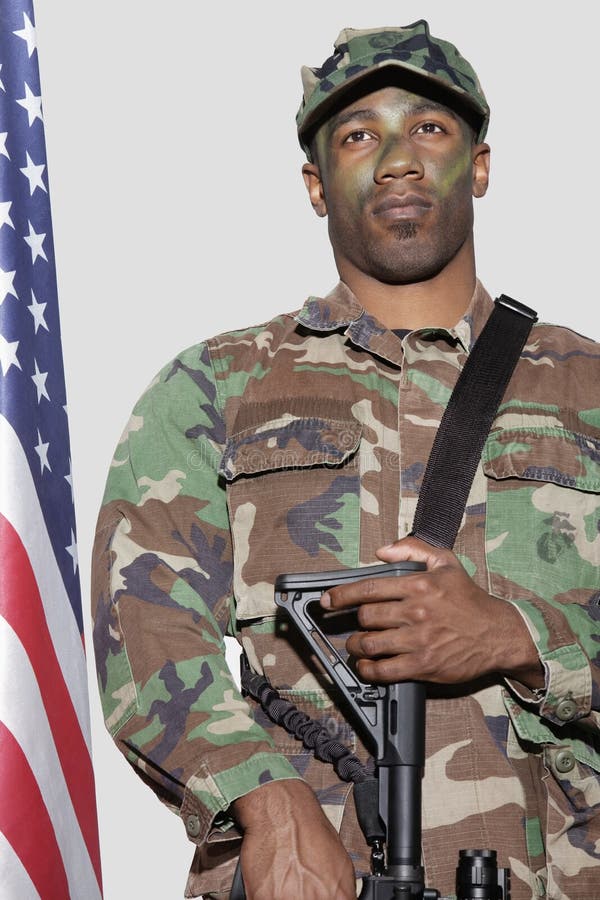 Soldat för USA Marine Corps med anseende för gevär för anfall M4 vid amerikanska flaggan över grå bakgrund arkivfoto Soldat för USA Marine Corps med anseende för gevär för anfall M4 vid amerikanska flaggan över grå bakgrund arkivfoto