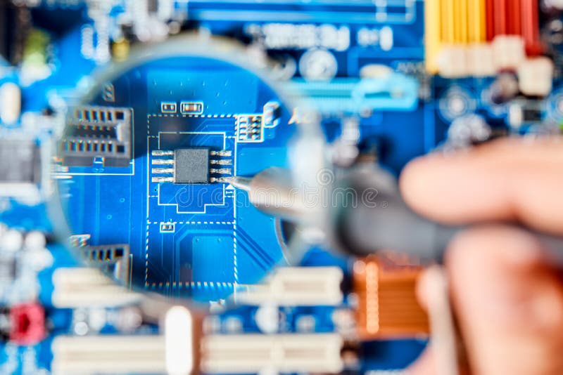 Soldering iron broken electronic board through magnifying glass. Electronic parts of pc: motherboard, microchip