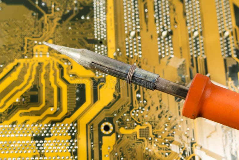 Soldering Iron with Red Handle Over a Printed Circuit Board Stock Image