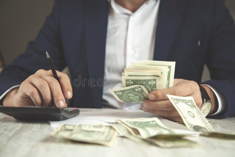 Soldi di mano dell'uomo con il calcolatore immagini stock Soldi di mano dell'uomo con il calcolatore immagini stock