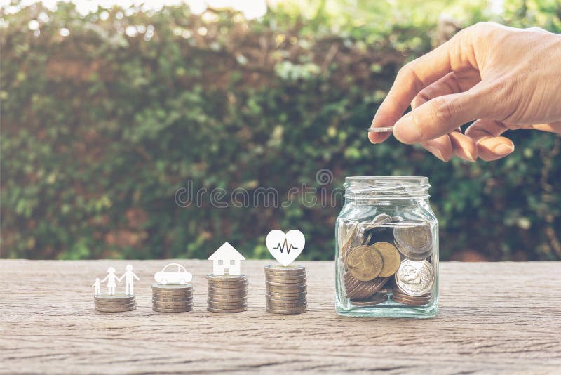 Savings money for family life concepts. Hand holding coin on a full money in glass jar and family member, car, house, healthy on coins. Depicts saving for wealth and life. fundraising concept. Savings money for family life concepts. Hand holding coin on a full money in glass jar and family member, car, house, healthy on coins. Depicts saving for wealth and life. fundraising concept