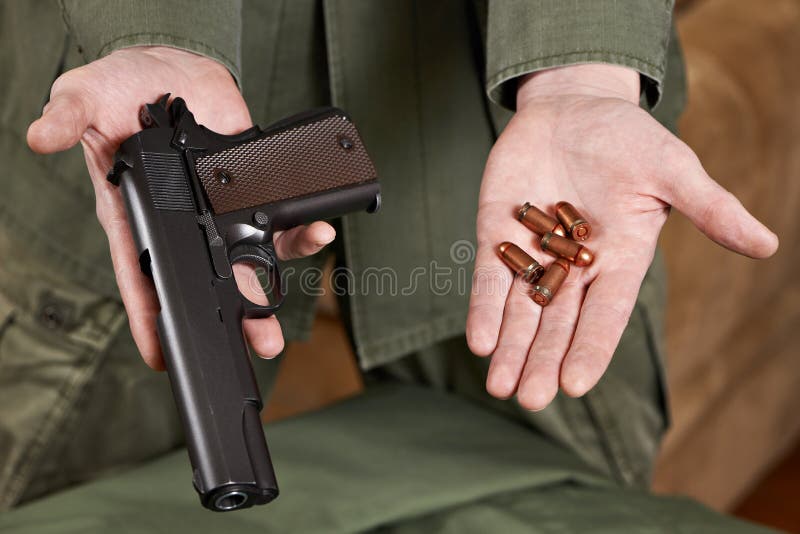 Soldier demonstrates Colt pistol and cartridges to it stock photo Soldier demonstrates Colt pistol and cartridges to it stock photo
