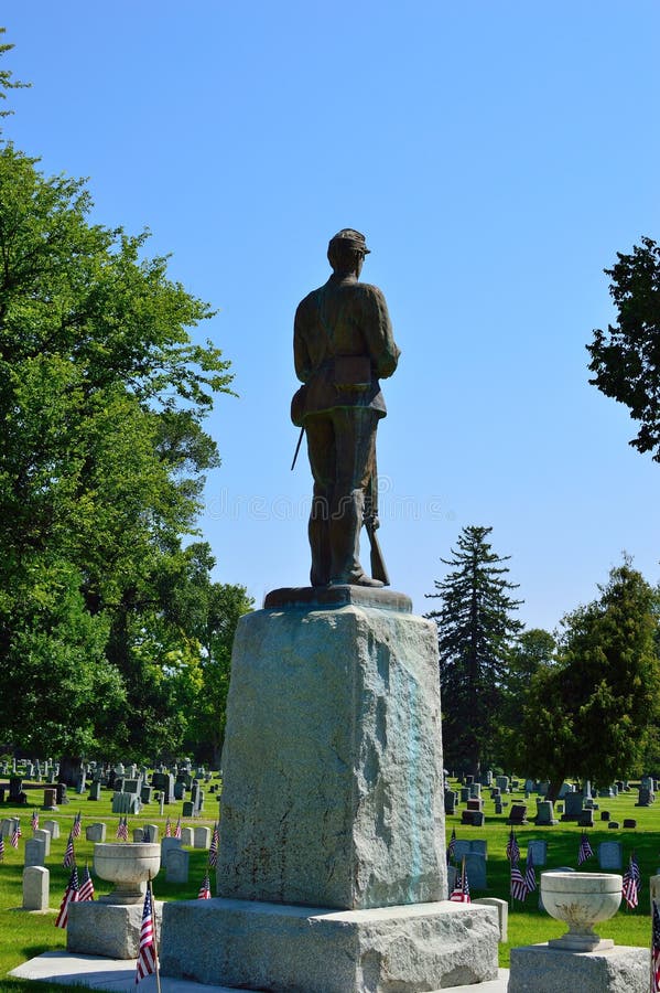 Soldier in heaven - statue in cemetery blue sky with memorial veterans independence day flags. Soldier in Heaven. Statue of soldier against puffy white clouds in royalty free stock photography Soldier in heaven - statue in cemetery blue sky with memorial veterans independence day flags. Soldier in Heaven. Statue of soldier against puffy white clouds in royalty free stock photography