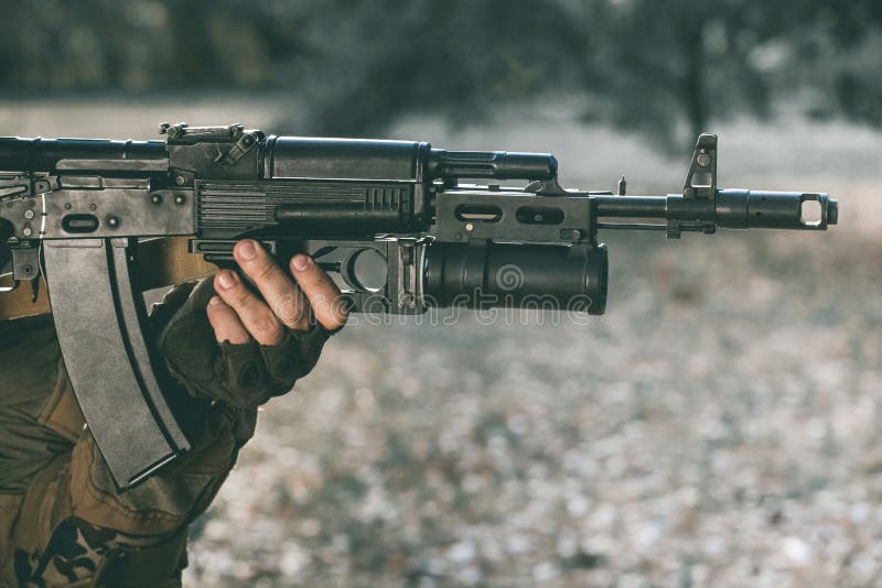 The soldier in the performance of tasks in camouflage and protective gloves holding a gun.