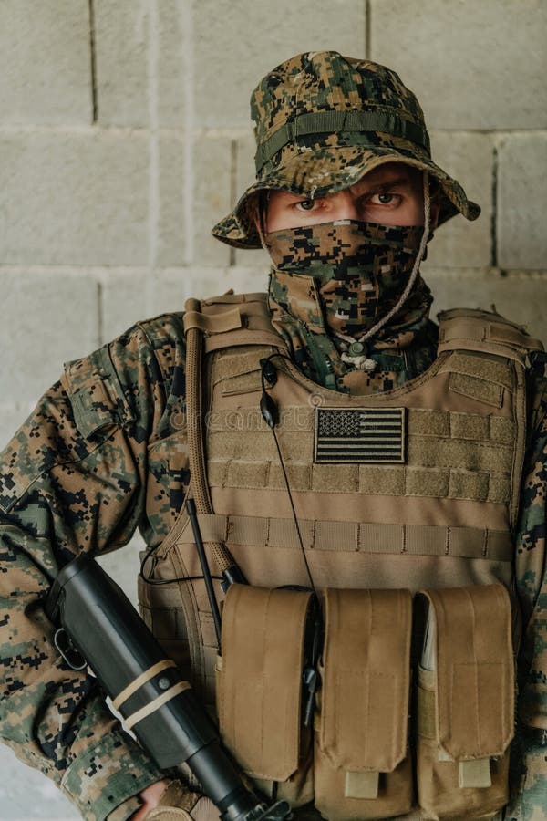 A Soldier in Uniform Stands in Front of a Stone Wall in Full War Gear