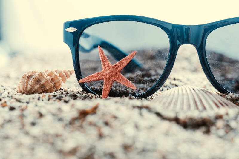 Sunglasses and starfish on sand with seashells. Travel concept. Sunglasses and starfish on sand with seashells. Travel concept