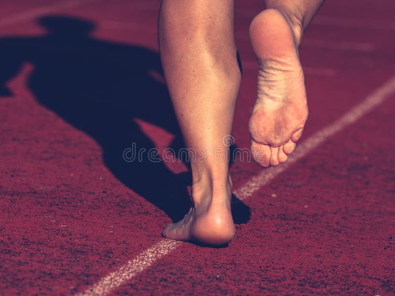 Solid Bare Feet of a Hard Training Woman Runs Along Running Track Stock