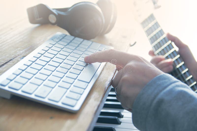 Solid tekniker som spelar gitarren, piano och blandar någon ljudsignal i en hem- studio royaltyfri bild Solid tekniker som spelar gitarren, piano och blandar någon ljudsignal i en hem- studio royaltyfri bild