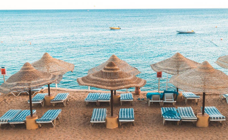 Solnedgång över semesterortområdet av Röda havetkusten i Egypten Ferie i Sharm el Sheikh. Härlig solig strand och slags solskydd på kusten av Röda havet i staden av Sharm el Sheikh, Egypten Turist- rekreationsområde på den Sinai halvön