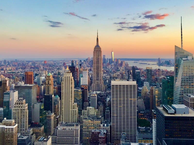 View of the Empire State Building at Sunset on a beautiful sunny summer day. All of lower Manhattan and One World Trade skyscraper can be seen in background. View of the Empire State Building at Sunset on a beautiful sunny summer day. All of lower Manhattan and One World Trade skyscraper can be seen in background.