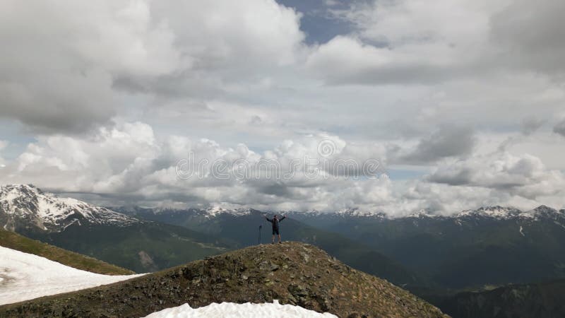 Solo backpacker spreads arms on mountain top, enjoys Svaneti views. Traveler embraces freedom, nature, clear sky in stock video footage
