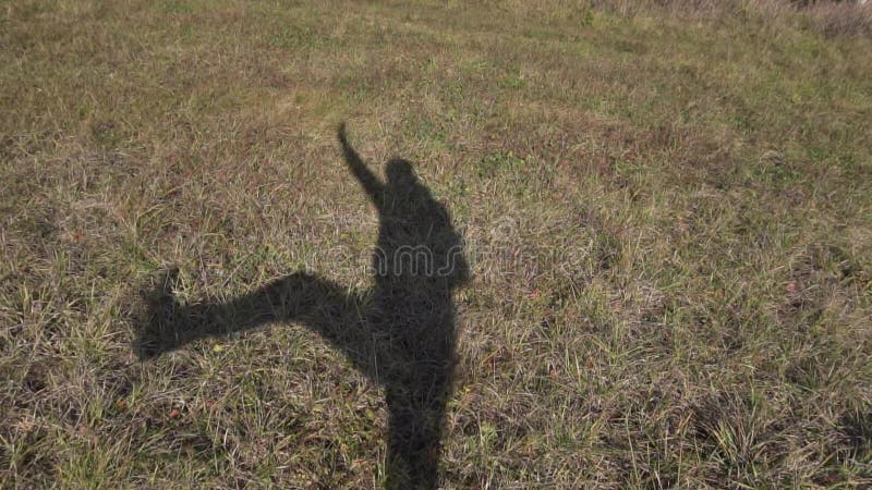 Sombra de hombre delgado sobre suelo marrón claro, cubierto de hierba gruesa