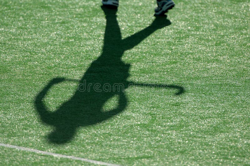 The shadow of a field hockey player as they run down the pitch during a competition. The shadow of a field hockey player as they run down the pitch during a competition.