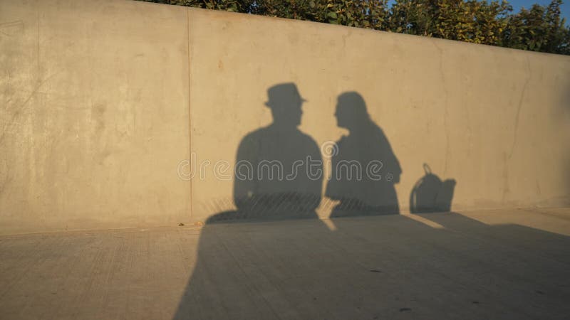 Sombras de jóvenes y mujeres besándose a la luz del sol reflexionando sobre la pared. silueta de una pareja romántica enamorada al