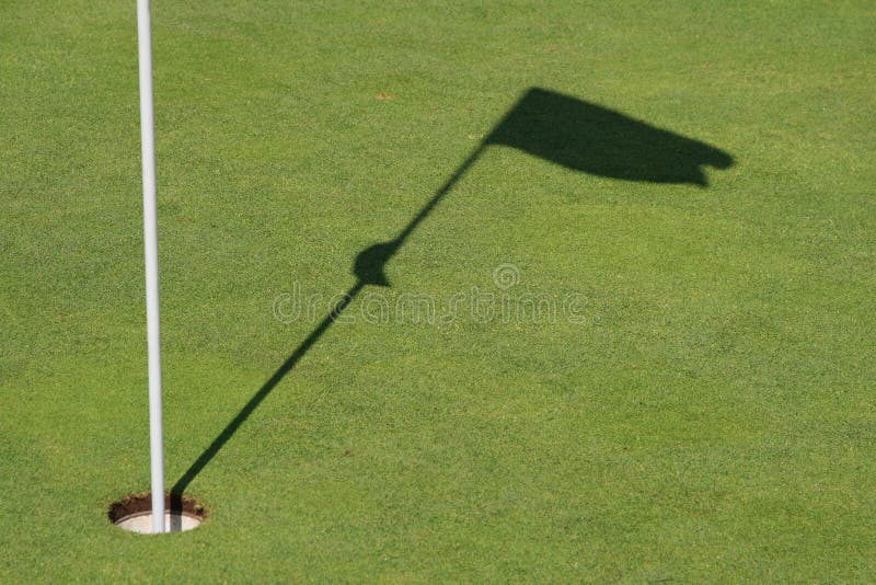 Shadows of a golf flag on this perfectly manicured green. Shadows of a golf flag on this perfectly manicured green