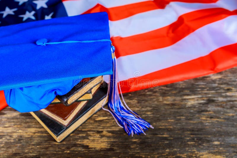 sombrero azul de la graduación en los libros con el fondo de la bandera americana fotografía de archivo sombrero azul de la graduación en los libros con el fondo de la bandera americana fotografía de archivo