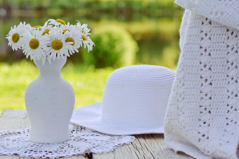 Sombrero, bufanda y ramo blancos de manzanilla en florero imagen de archivo Sombrero, bufanda y ramo blancos de manzanilla en florero imagen de archivo