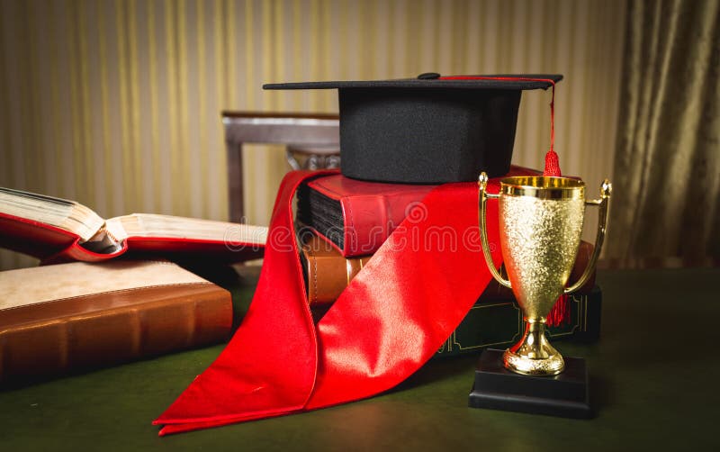 Sombrero de la graduación, cinta roja y taza de oro para el primer lugar fotografía de archivo libre de regalías Sombrero de la graduación, cinta roja y taza de oro para el primer lugar fotografía de archivo libre de regalías