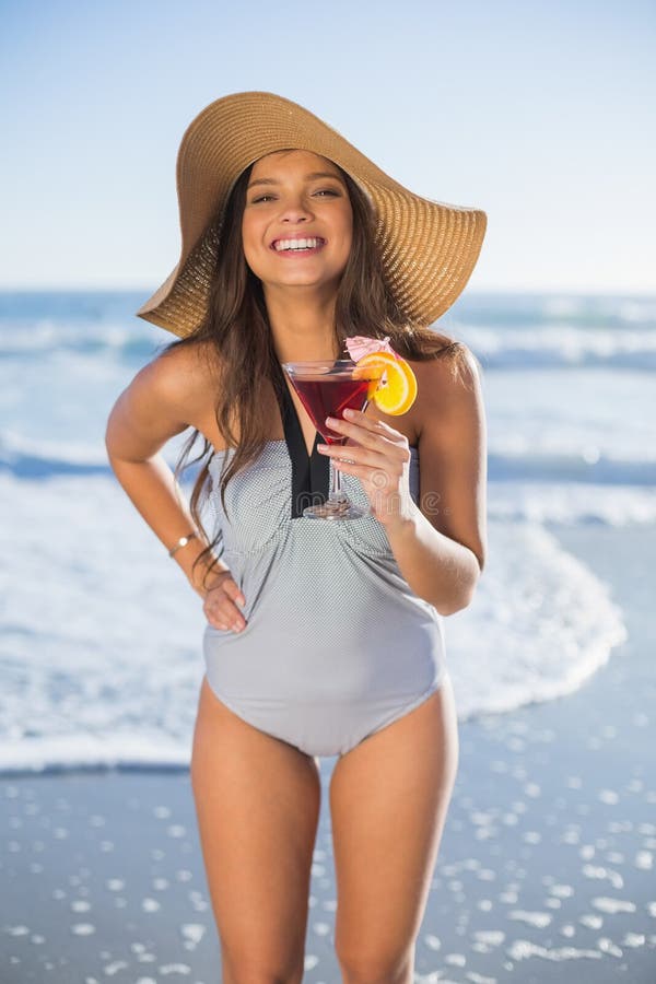 Sombrero de paja de la mujer que lleva hermosa que sostiene el cóctel foto de archivo libre de regalías Sombrero de paja de la mujer que lleva hermosa que sostiene el cóctel foto de archivo libre de regalías
