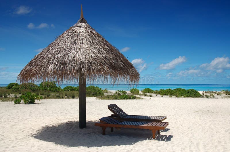 Sunshade with deckchair on a tropical beach with blue sky and white sand. Sunshade with deckchair on a tropical beach with blue sky and white sand