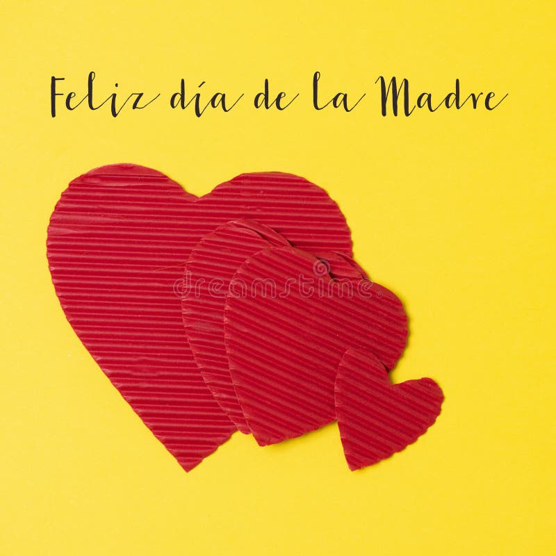 Hearts and text happy mothers day in spanish. Some red hearts and the text feliz dia de la madre, happy mothers day written in spanish, on a yellow background royalty free stock image