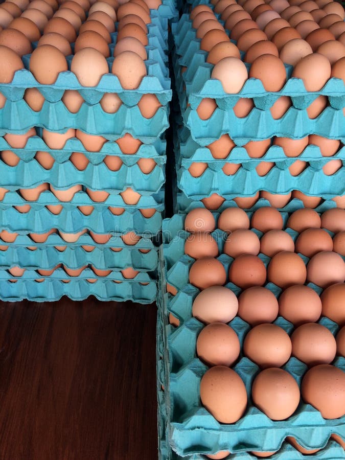 Some stacked free range eggs on green tray on wooden table