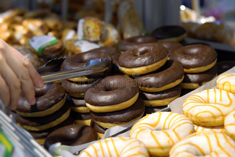 Someone takes a donut from a shelf in the confectionery department royalty free stock photo Someone takes a donut from a shelf in the confectionery department royalty free stock photo
