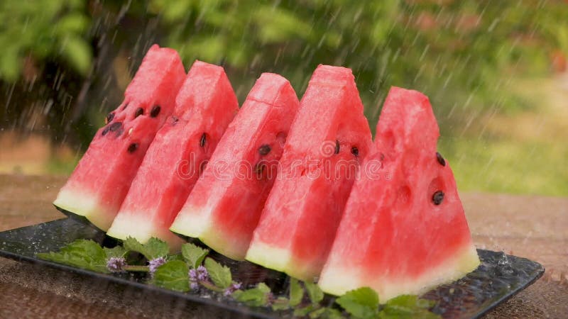 Sommardusch som häller över vattenmelonskivor