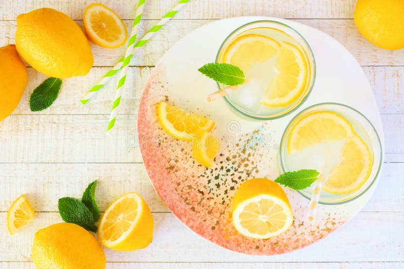 Sommarlemonad på en rosa och vit tjänande som platta, ovanför sikt över vitt trä arkivbild Sommarlemonad på en rosa och vit tjänande som platta, ovanför sikt över vitt trä arkivbild