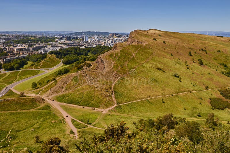 Sommarsikten av Salisbury brant klippa från Arthur ` s Seat i Holyrood parkerar med härligt grönt gräs och blå himmel i Edinburg, royaltyfria bilder Sommarsikten av Salisbury brant klippa från Arthur ` s Seat i Holyrood parkerar med härligt grönt gräs och blå himmel i Edinburg, royaltyfria bilder