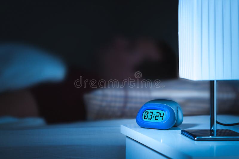 Sommeil d'homme de bâti Réveil de Digital sur le nightstand photographie stock