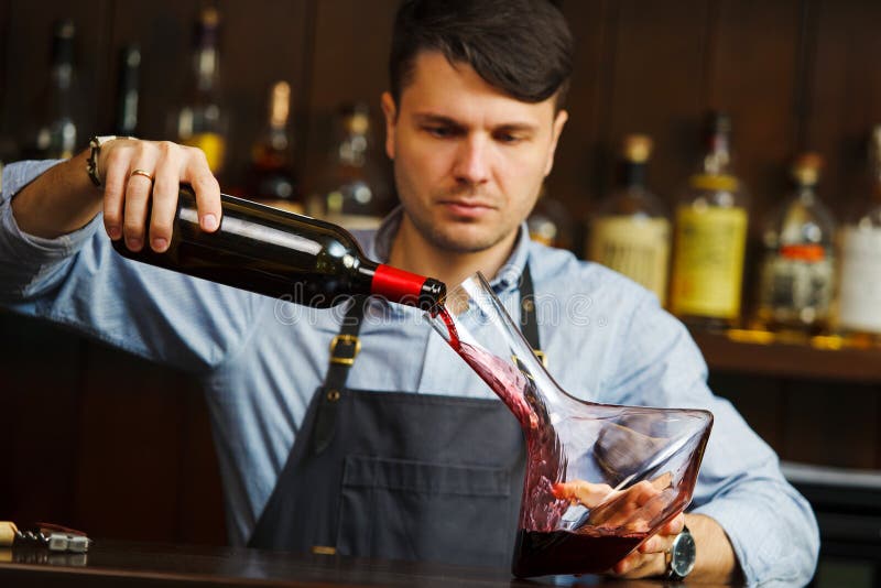 Sommelier dolewania wino w szkło od dekantatoru męski kelner obraz stock Sommelier dolewania wino w szkło od dekantatoru męski kelner obraz stock