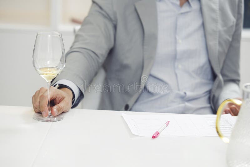Sommelier masculin față degustare vin alb în sticlă și face note la cardul degustation în timpul instruirii sommelier. royalty free stock images
