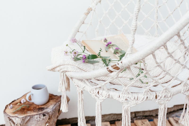 Summer hygge scene with hammock chair, book and flowers. Cozy place for weekend relax in the garden. Summer hygge scene with hammock chair, book and flowers. Cozy place for weekend relax in the garden.